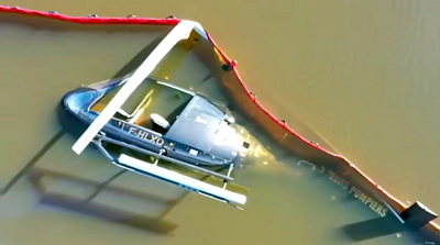 L'épave de l'Ecureuil F-HLXO "Morane 29" semi immergée dans le lac entourée d'un barrage flottant antipollution - Photo © TF1