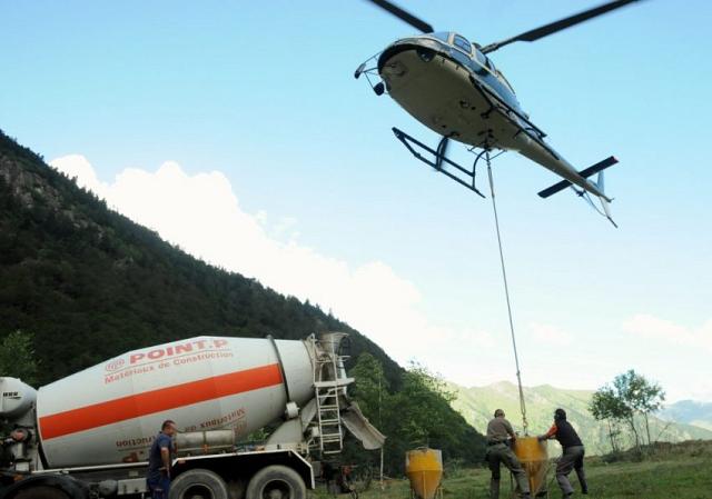 Pendant que l'hélicoptère maintient un vol stationnaire, les mécaniciens au sol changent la benne en béton - Photo DDM, Florent Raoul. 