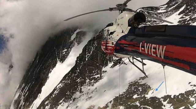 A l'approche de l'alpiniste épuisé, et des Sherpas qui l'assistent au sol (flèche bleue)