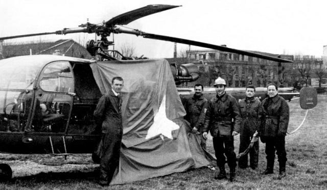 Alouette 3 F-ZBDC BSPP après la mission - Équipage Marcel GACOIN, pilote à gauche et Jean-Pierre Crolotte (à confirmer), mécanicien à droite du drapeau, avec au premier plan le sergent Raymond Belle (Sapeur-Pompier‌ en casque) qui est descendu au bout du câble pour effectuer cette opération, le 19 janvier 1969 - Photo DR collection SCPMT (Section Conservation du Patrimoine, Mémoire et Traditions) 