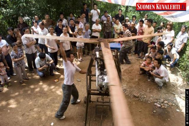 In this photo taken Aug. 1, 2009, villagers watch 22-year-old Wu Zhongyuan turning blades of his homemade helicopter in preparation for a maiden flight in Songxian, in central China's Henan province. Wu assembled his helicopter with a 150cc motorbike's engine, a steel cage, and wooden rotor blades. Later, the local government stopped the flight for safety issues.
